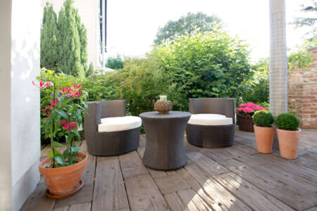 Terrasse mit Holzoptik-Belag, Sitzmöbeln und Pflanzkübeln