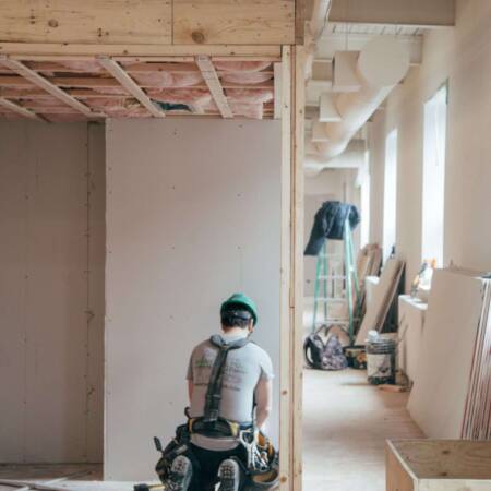 Bauarbeiter beim Innenausbau eines Gebäudes mit sichtbarem Holzgebälk