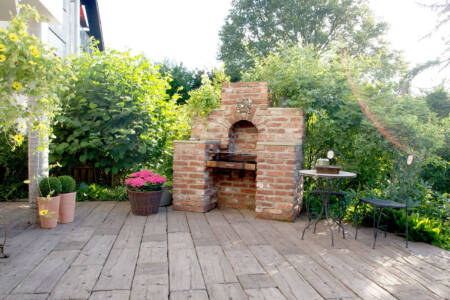 Terrasse mit gemauertem Grill und Holzbelag im Gartenbereich
