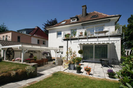 Natursteinterrasse mit Garten am Einfamilienhaus bei sonnigem Wetter